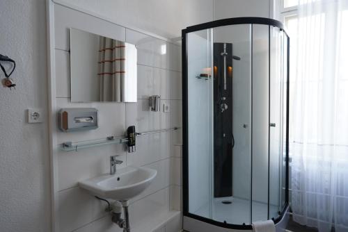 uma casa de banho com uma cabina de duche em vidro e um lavatório. em City Pension Berlin em Berlim
