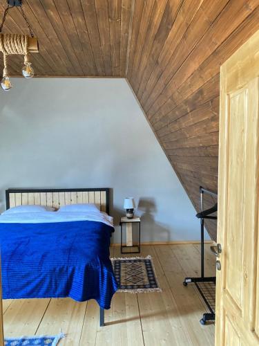 a bedroom with a blue bed and a wooden ceiling at Deka Achkhoti in Stepantsminda