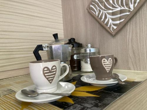 two coffee cups on a table with a coffee maker at S'imbustHouse in Oristano