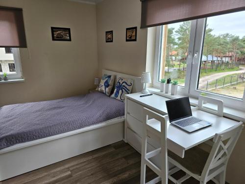 a bedroom with a bed and a desk with a laptop at Apartament Bałtyk in Rowy