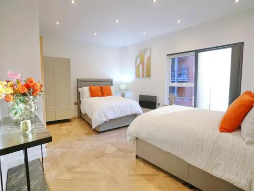 a bedroom with two beds and a vase of flowers on a table at Pass the Keys Large Central Flat Walk To City Centre In 5 Mins in Manchester