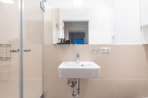 ein weißes Bad mit einem Waschbecken und einer Dusche in der Unterkunft HM • Cosy 1BR Near Westbahnhof in Wien
