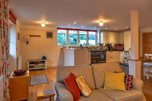 a living room with a couch and a kitchen at Finest Retreats - Lower School Cottages in Minehead
