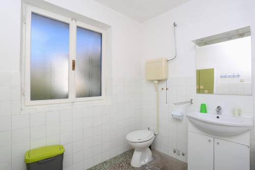 a white bathroom with a toilet and a sink at Apartments Marija 1000 in Rabac
