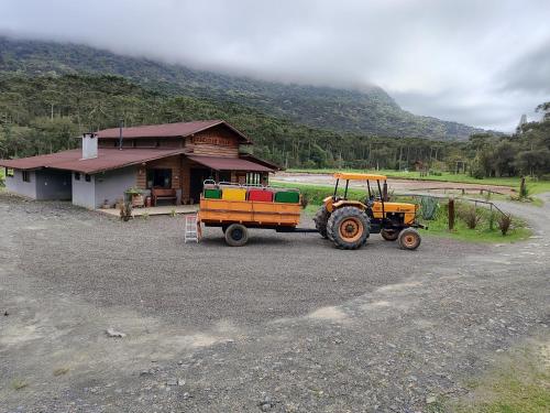 a tractor is parked in front of a building at Pousada Vale da Imbuia chalé para temporada in Urubici