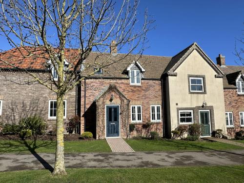 a large brick house with a tree in front of it at Willow Cottage - Part of the The Bay Filey Holiday Village with pool, gym and direct beach access, pub, restaurant, tennis and meadows walks in Reighton