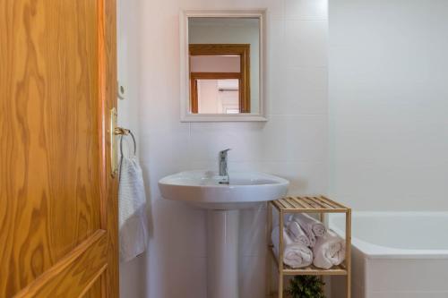 Un baño blanco con lavabo y espejo. en URBANIZACIÓN COPACABANA - La Manga del Mar Menor KM2 - Vistas a Mediterráneo Dormitorio doble y sofá-cama, en La Manga del Mar Menor