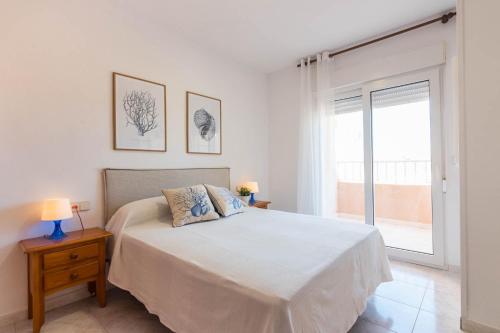 a white bedroom with a bed and a window at URBANIZACIÓN COPACABANA - La Manga del Mar Menor KM2 - Vistas a Mediterráneo Dormitorio doble y sofá-cama in La Manga del Mar Menor