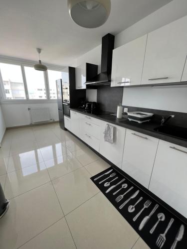 a kitchen with white cabinets and a black counter top at Super 4 Pièces refait à neuf in Villeurbanne