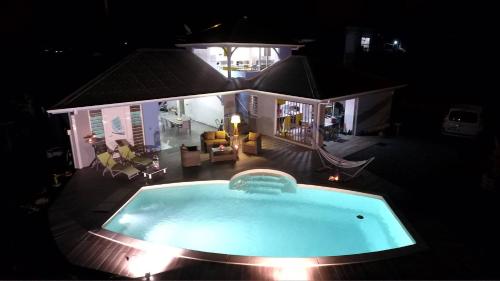 - une piscine en face d'une maison la nuit dans l'établissement L'Escale Créole, à Rivière-Salée
