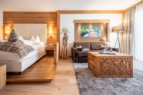 um quarto de hotel com uma cama e um sofá em Hotel Chalet Das Alpenschlössel em Saltusio