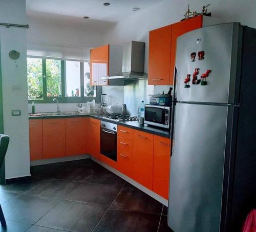 eine Küche mit orangefarbenen Schränken und einem Kühlschrank aus Edelstahl in der Unterkunft Peaceful and lovely apartment! Front beach in Las Terrenas