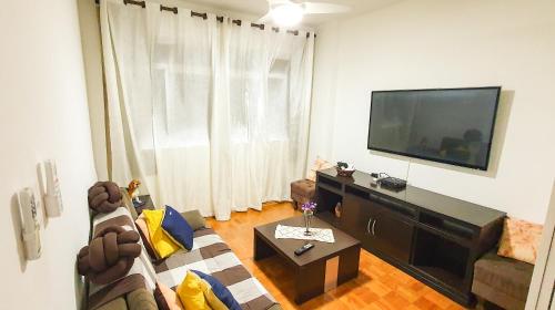 a living room with a couch and a tv at Santos Gonzaga - Vista mar & localização perfeita in Santos