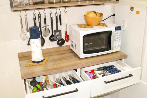 a microwave on a shelf in a kitchen with utensils at Santos Gonzaga - Vista mar & localização perfeita in Santos