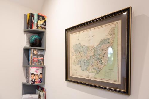 a framed map of china on a wall next to a book shelf at The Lily Pad Suffolk in Thornham Magna