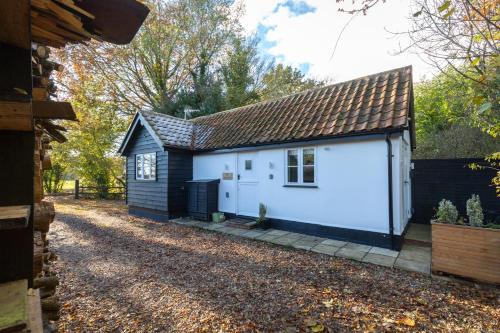 um pequeno barracão branco com um telhado castanho em The Lily Pad Suffolk em Thornham Magna