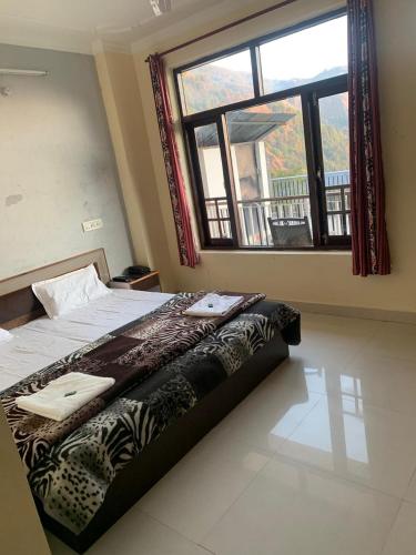 een slaapkamer met een bed en een groot raam bij Om Tara Homestay in Dharamshala
