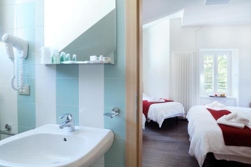a bathroom with a sink and a mirror and two beds at Hotel Croda Rossa in Carbonin