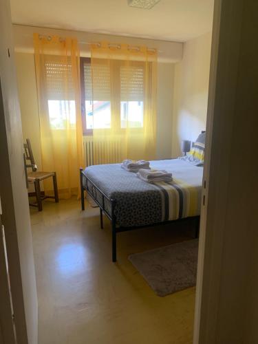 Schlafzimmer mit einem Bett, einem Stuhl und Fenstern in der Unterkunft Villa Cécilia in Lourdes