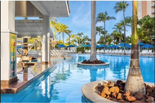 einen Pool in einem Resort mit Palmen in der Unterkunft Hotel Aruba in Palm-Eagle Beach