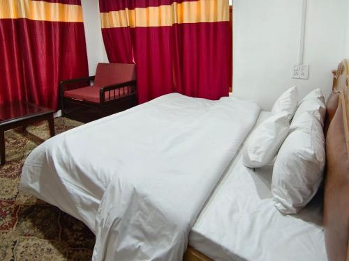 a bedroom with a white bed with a red curtain at Royal galaxy in Pahalgām