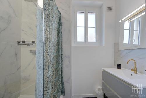 une salle de bain avec un rideau de douche et un lavabo dans l'établissement L'oiseau blanc / central - piscine du lac, à Tours