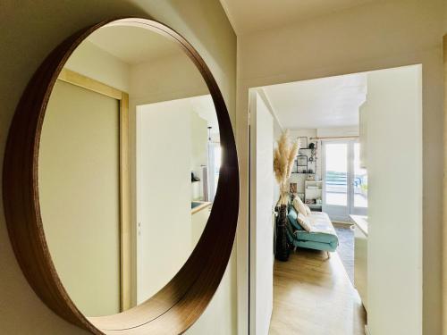 - un grand miroir rond sur le mur du salon dans l'établissement Appartement rénové dans résidence de vacances proche océan Les Sables, à Les Sables-dʼOlonne