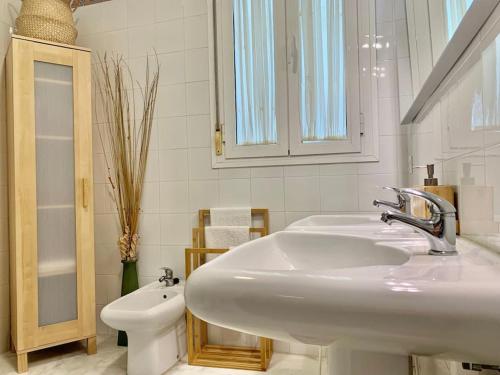 Baño blanco con lavabo y aseo en Cozy Comfy, en Sevilla