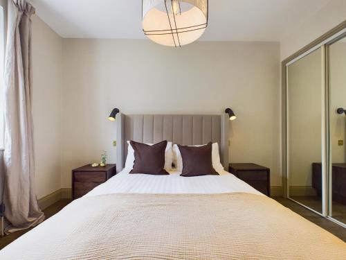 a bedroom with a large bed with brown pillows at Be London - The St John's Wood Residences in London