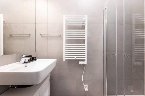 ein weißes Bad mit einem Waschbecken und einer Dusche in der Unterkunft HM • 1BR Oasis with Easy City Access in Wien