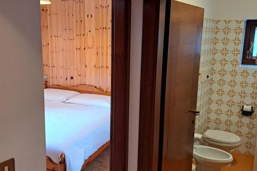 Un dormitorio con una cama y un baño con inodoro. en Appartamento Cialuzin, en Pieve di Cadore