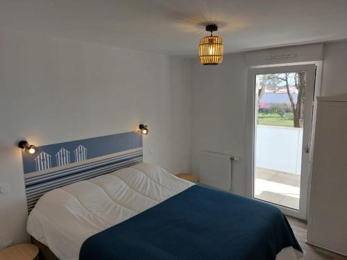 - une chambre avec un lit bleu et blanc et une fenêtre dans l'établissement Appartement neuf 40 m² 300 m de la mer, à Saint-Jean-de-Monts
