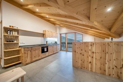 a kitchen with wooden cabinets and a vaulted ceiling at Parliflhof Apt Langfenn in Meltina