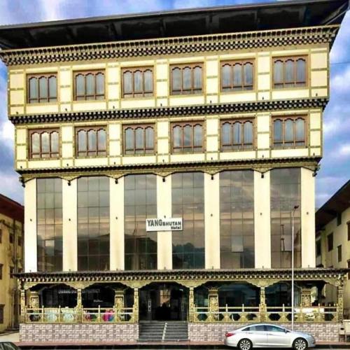 a large building with a car parked in front of it at Yang Bhutan Hotel in Paro