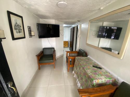 Habitación pequeña con cama, silla y TV. en Habitación Manizales #2, en Manizales