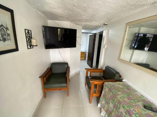 1 dormitorio con 1 cama, TV y silla en Habitación Manizales #2, en Manizales