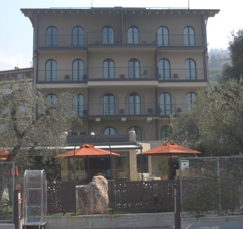 a large building with umbrellas in front of it at Hotel Ristorante Al Caminetto WorldHotels Crafted Adults Only in Torri del Benaco