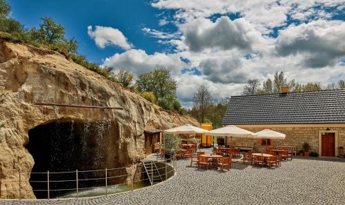 un patio con mesas y sombrillas junto a una pared de piedra. en Clearpoint, en Hořovičky