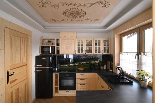 a kitchen with a black refrigerator and wooden cabinets at Domek pod Jaworem z balią in Witów