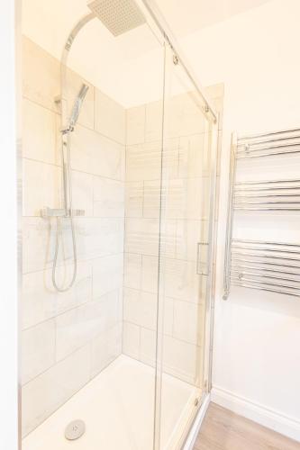La salle de bains est pourvue d'une douche avec une porte en verre. dans l'établissement Hedgehogs Home at Tove Valley Cottages, à Towcester