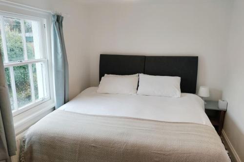 a bed in a bedroom with a large window at Quaint 3 bedroom Devon cottage in Honiton