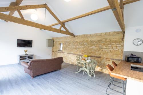 a living room with a brick wall and a table at Hedgehogs Home at Tove Valley Cottages in Towcester