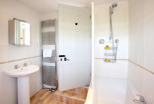 a white bathroom with a sink and a shower at The Old School in South Perrott