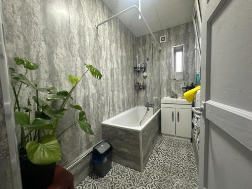 a bathroom with a tub and a potted plant at Shoreditch Rooms R2 in London