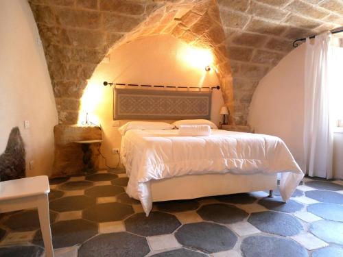 een slaapkamer met een bed met een stenen muur bij Suite della Contessa in Castelsardo