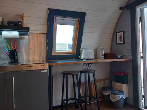 a kitchen with a counter and stools in a room at Riverside Pod, West Highland Way Holidays in Kinlochleven