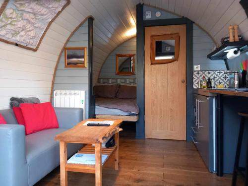 a living room with a couch and a table in a tiny house at Riverside Pod, West Highland Way Holidays in Kinlochleven