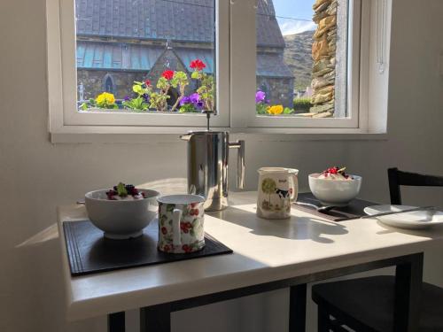 una mesa con dos tazones y dos ventanas en Cille Apartments, Ballyferriter village, en Ballyferriter