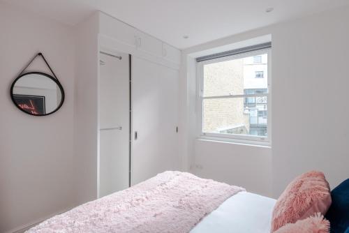 1 dormitorio con cama y ventana en Frankie Says - Stylish, spacious and centrally located near Oxford Circus, say hello to the gorgeous Goodge Vibes Only 1 BR apartment, en Londres
