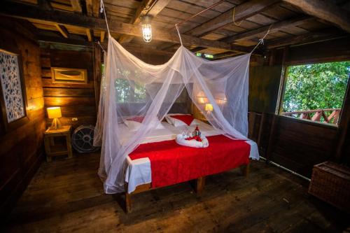 a bedroom with a red bed with a mosquito net at Morro Terco Hotel Boutique in Nuquí